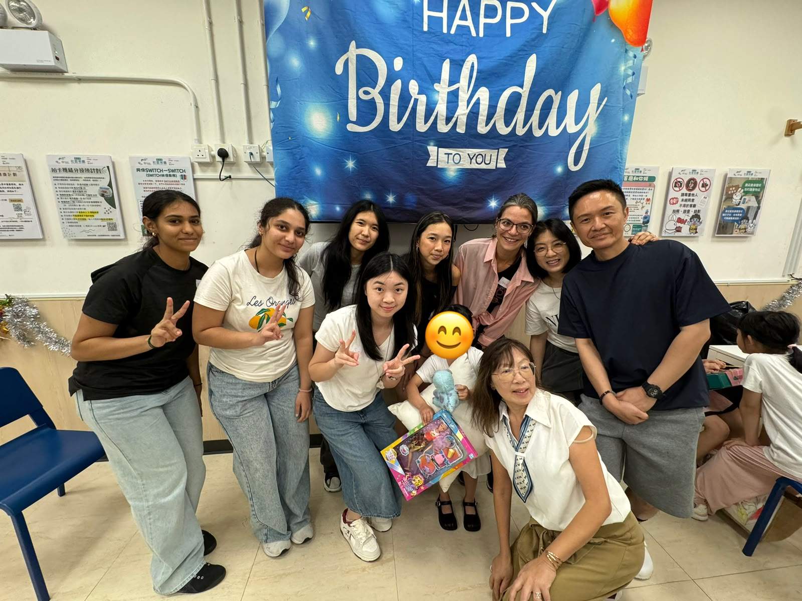 Adults and children pose together while holding gifts.
