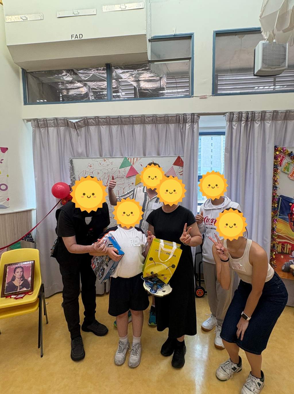 A child holding gifts while volunteers pose beside birthday decorations.