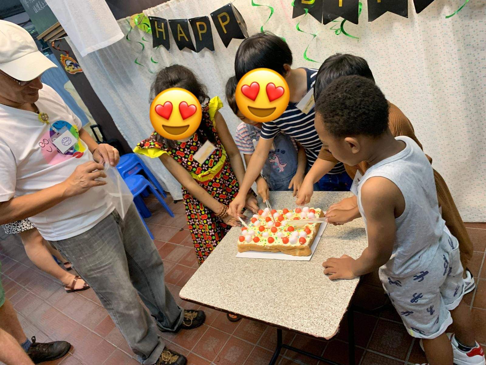 Children gather closely around a cake with lit candles.