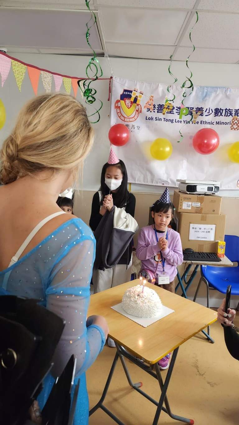 A child stands near a cake while adults watch.