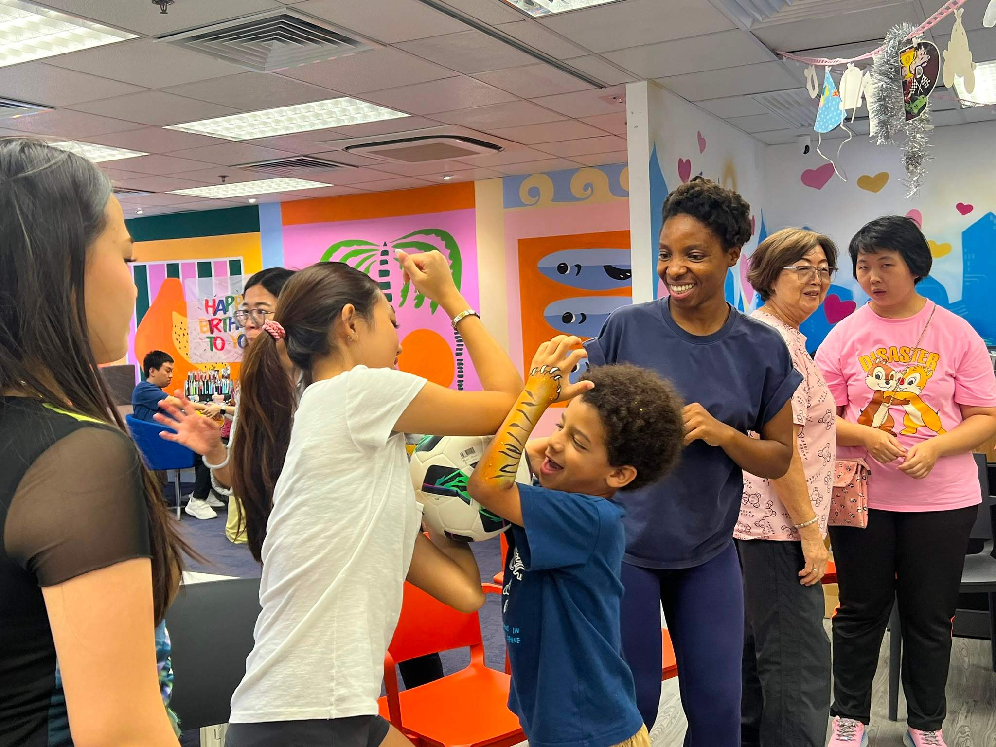Children and adults cluster together during a ball game.