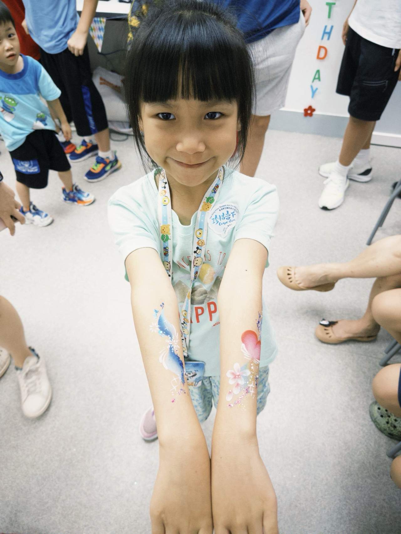 A child displays painted designs on both forearms.