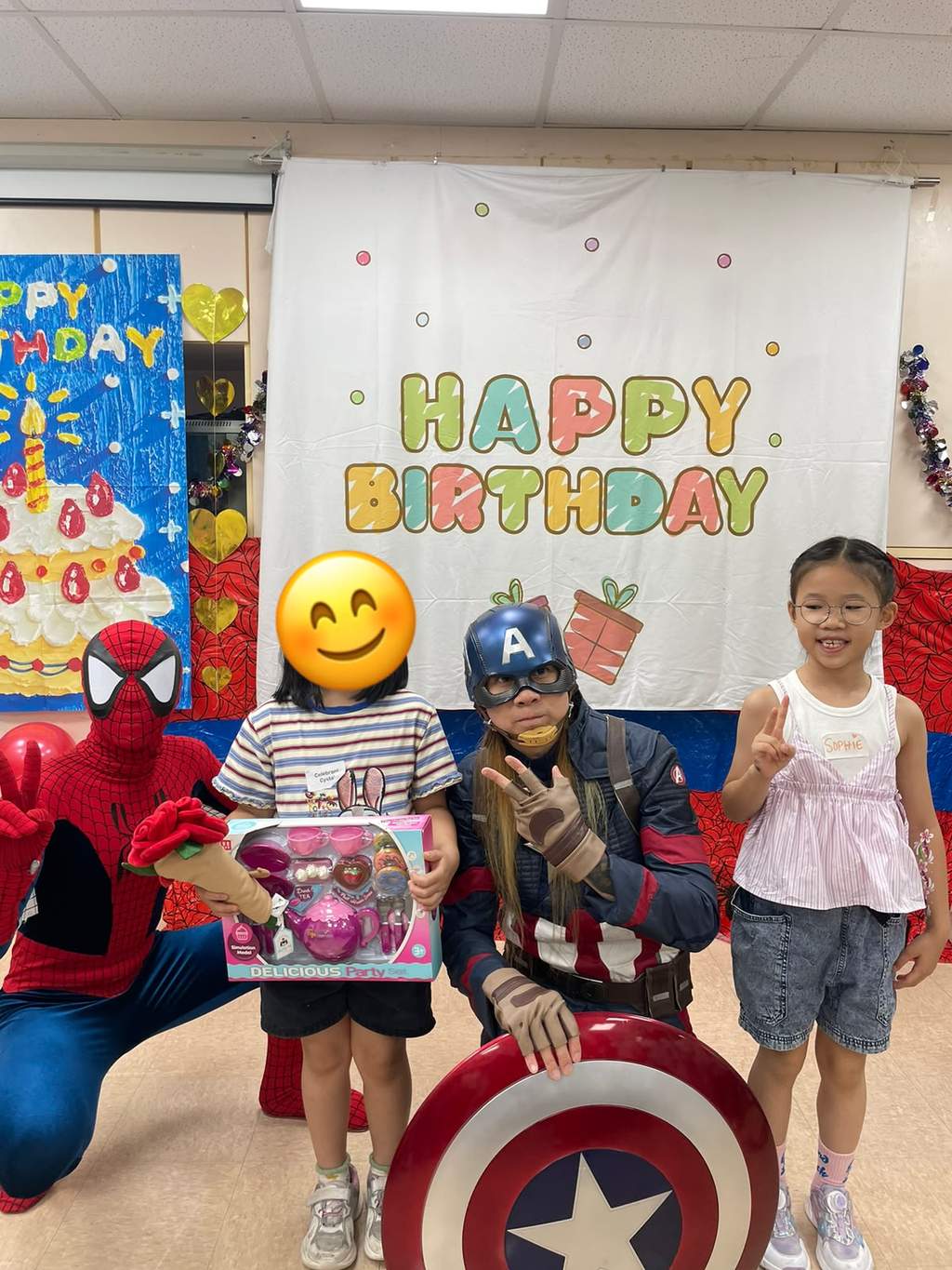Two costumed adults pose with children holding boxed gifts.