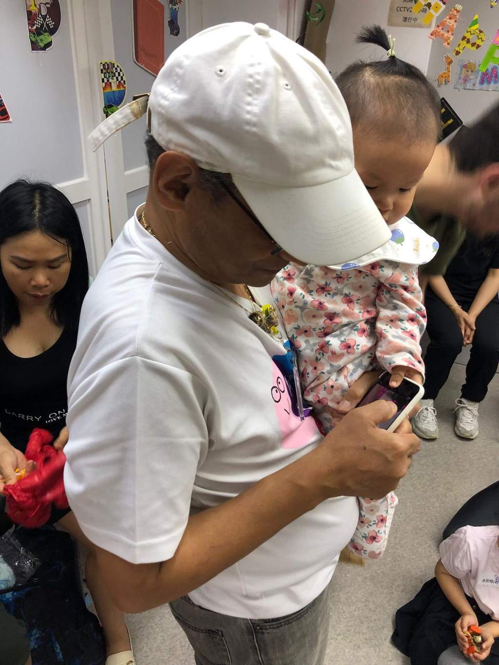 An adult prepares a small item while children gather nearby.
