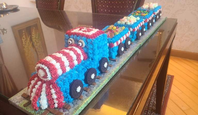 A candy-topped train birthday cake with Oreo wheels, by Bharti.