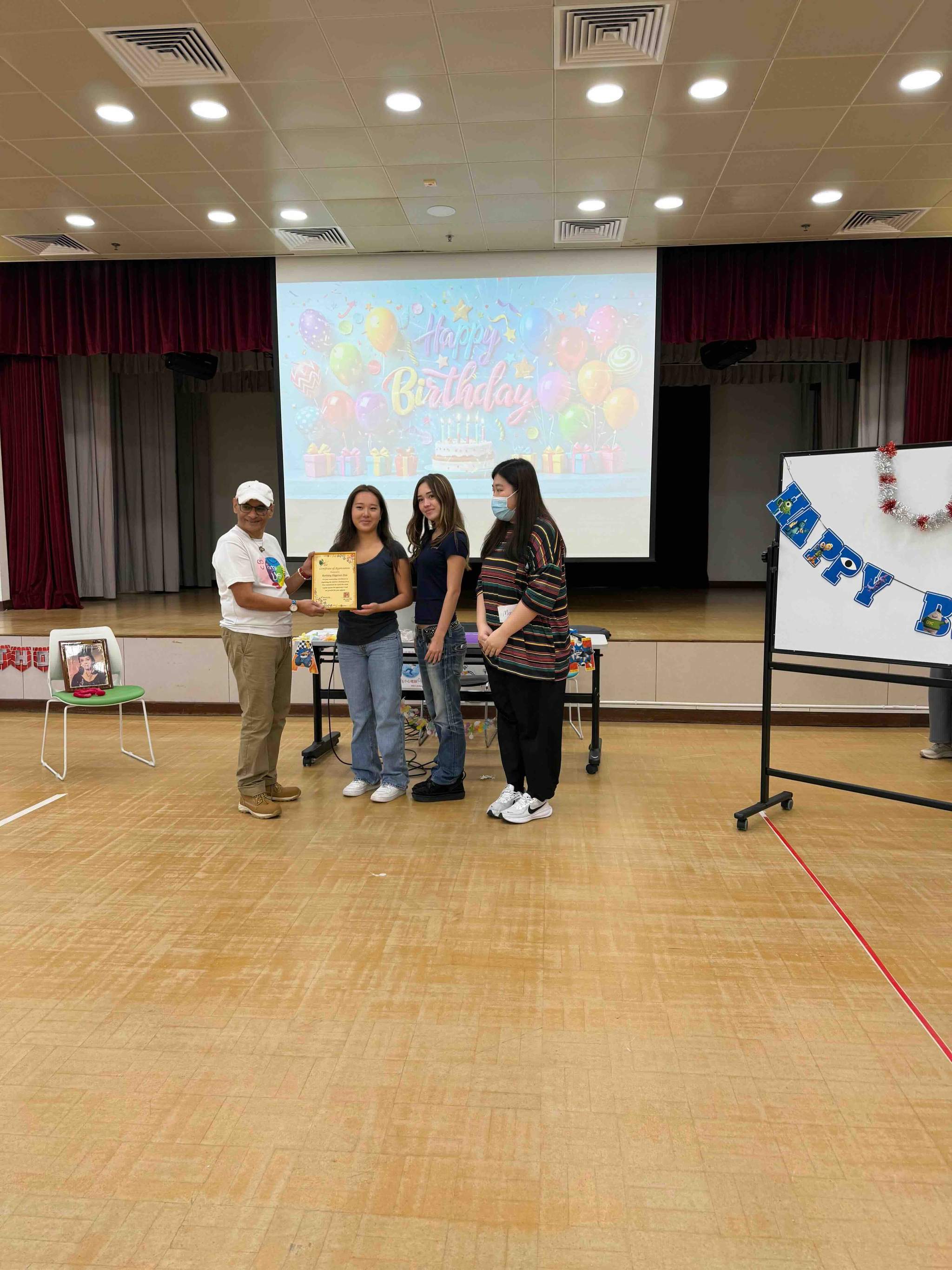 Four adults stand together on an indoor stage.