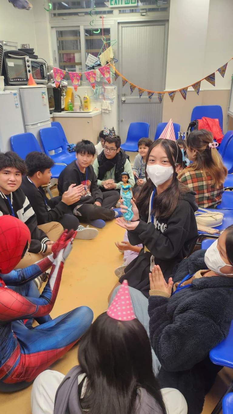 Adults and children sit in two rows during an activity.