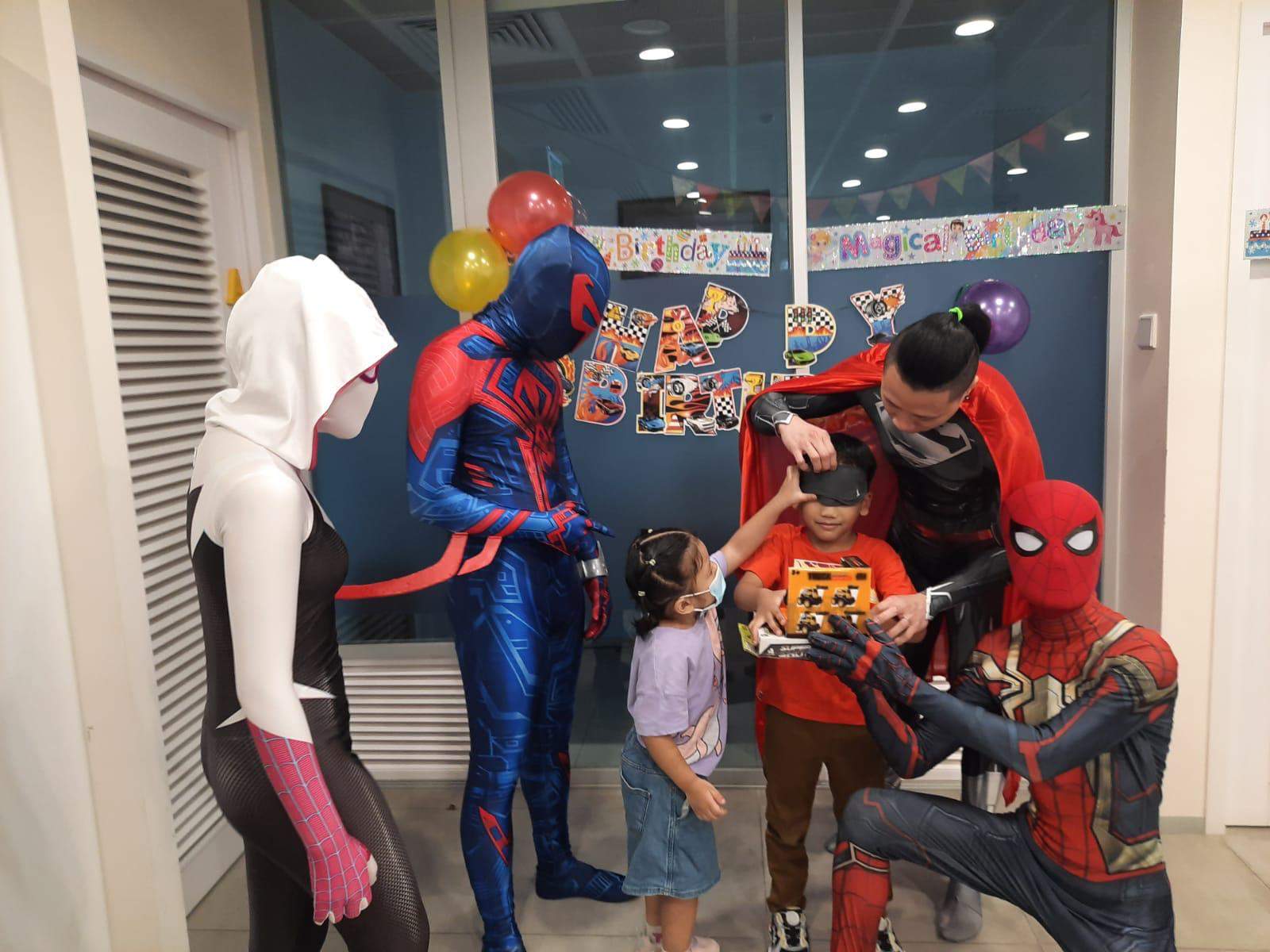 Costumed performers present a toy to two children.