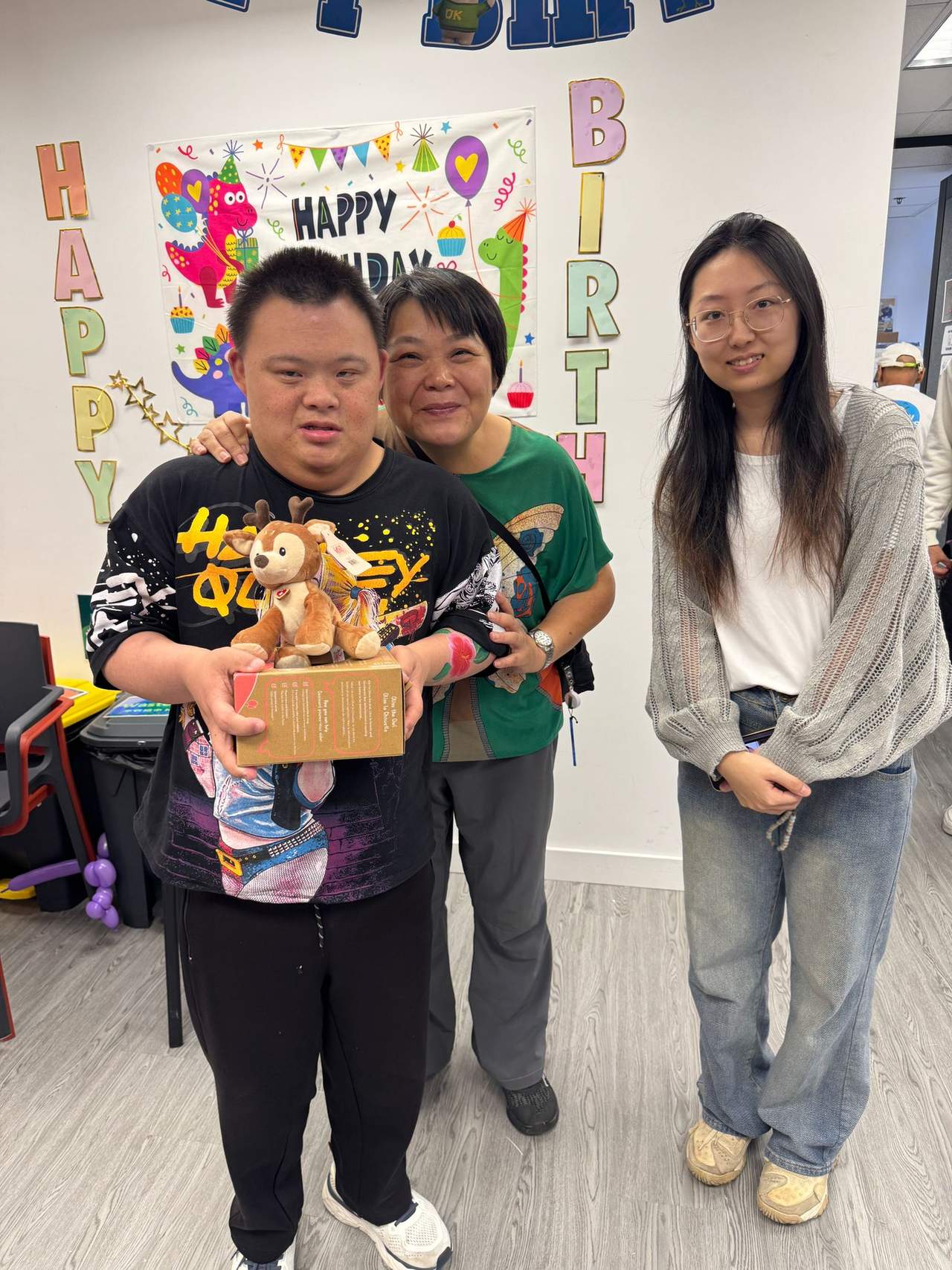 Two adults stand beside a person holding a gift basket.