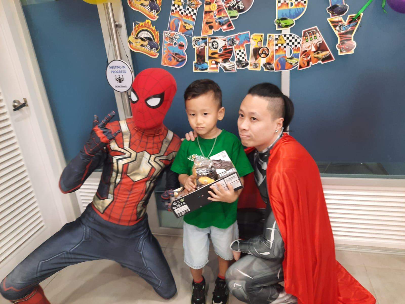 A costumed performer and adult kneel beside a child holding gifts.