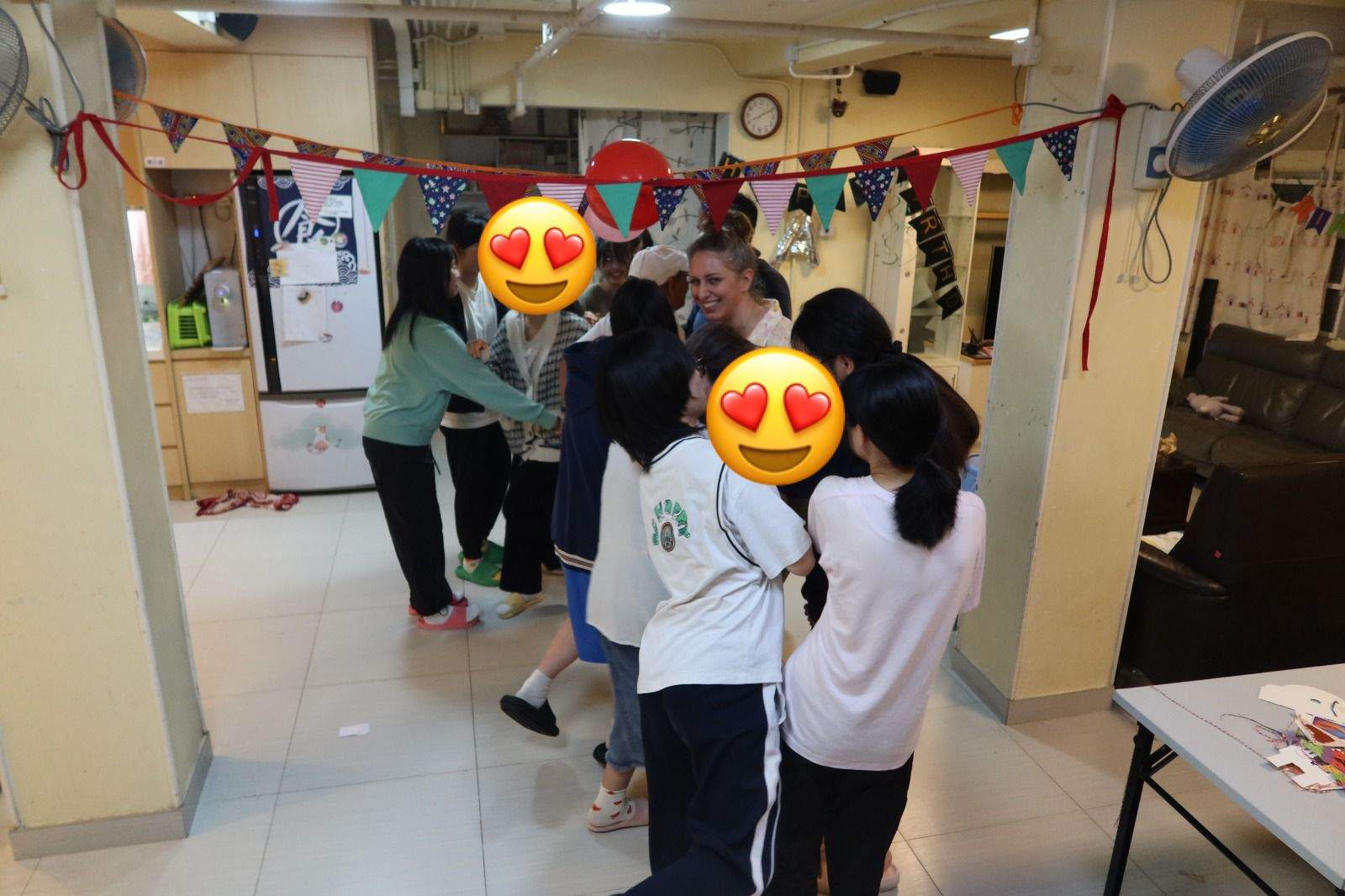 People stand together beneath bunting in a decorated room.