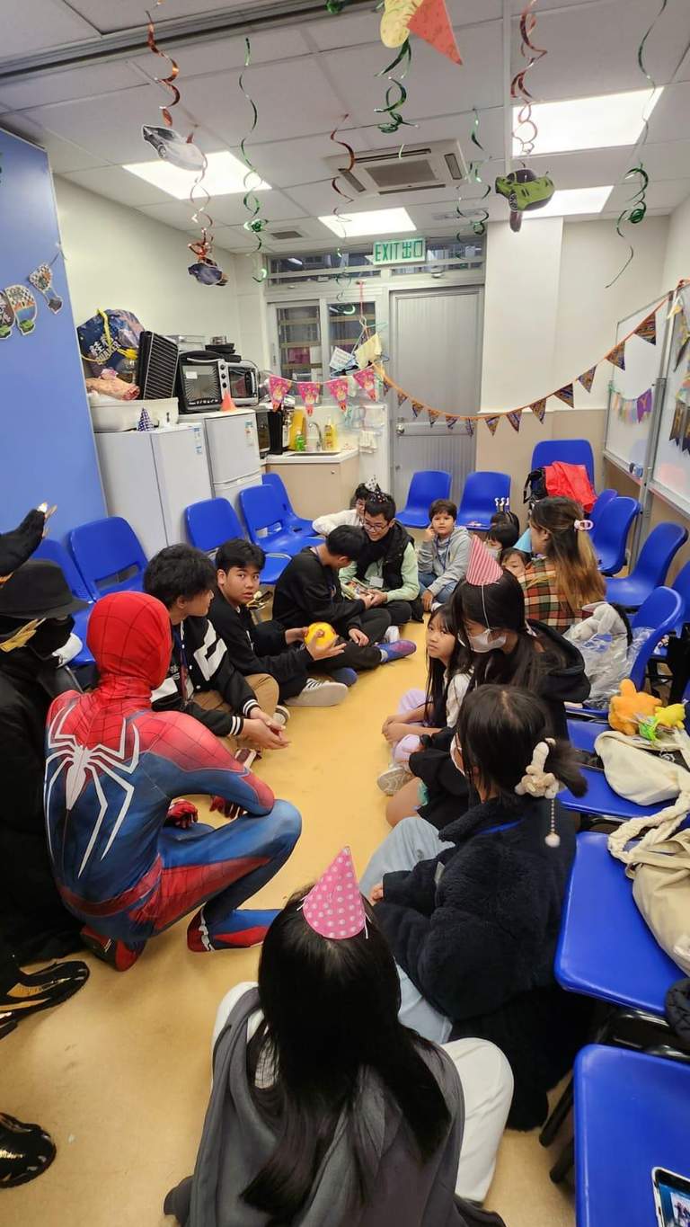 A costumed performer addresses a seated group in a narrow room.