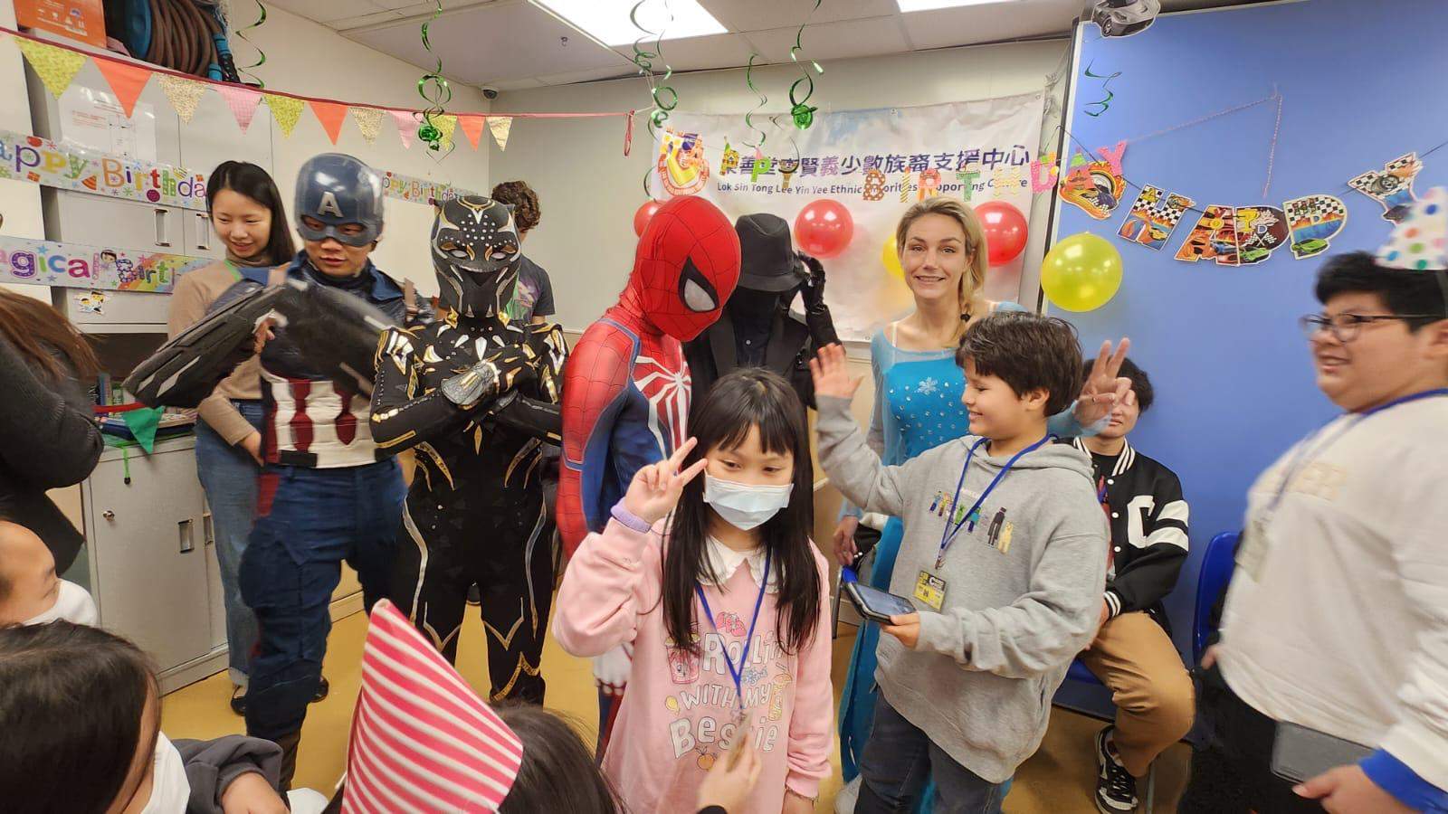 Costumed performers pose with children in the decorated room.