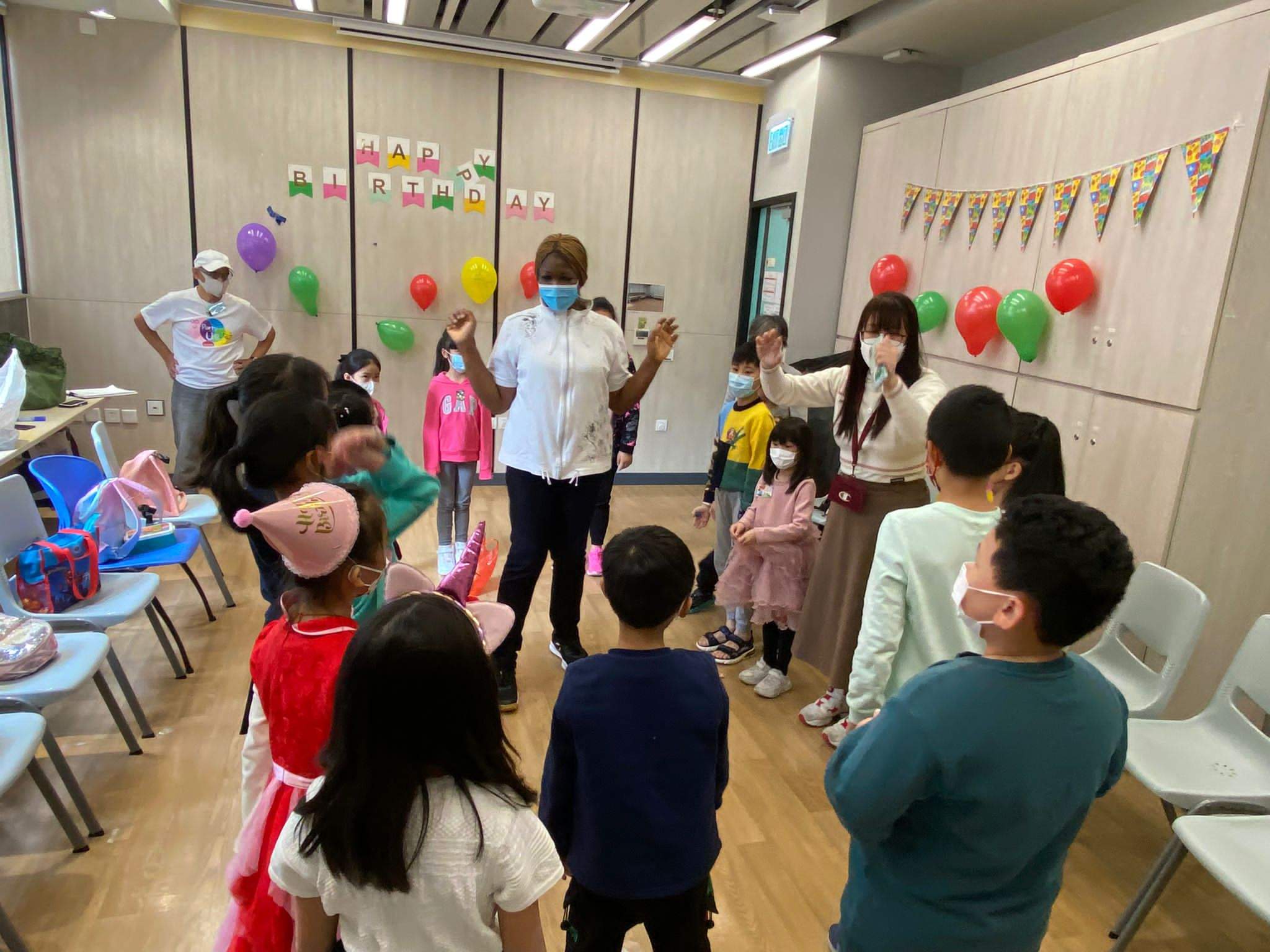 A Birthday Happiness Asia volunteer leading children in a game at a birthday party in a partner centre.
