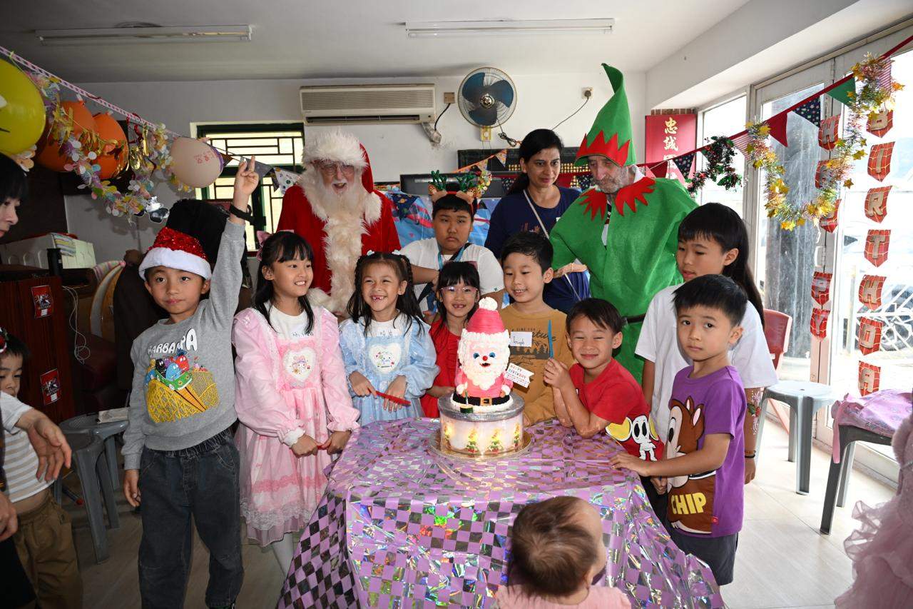 Children and costumed adults pose behind a festive cake.