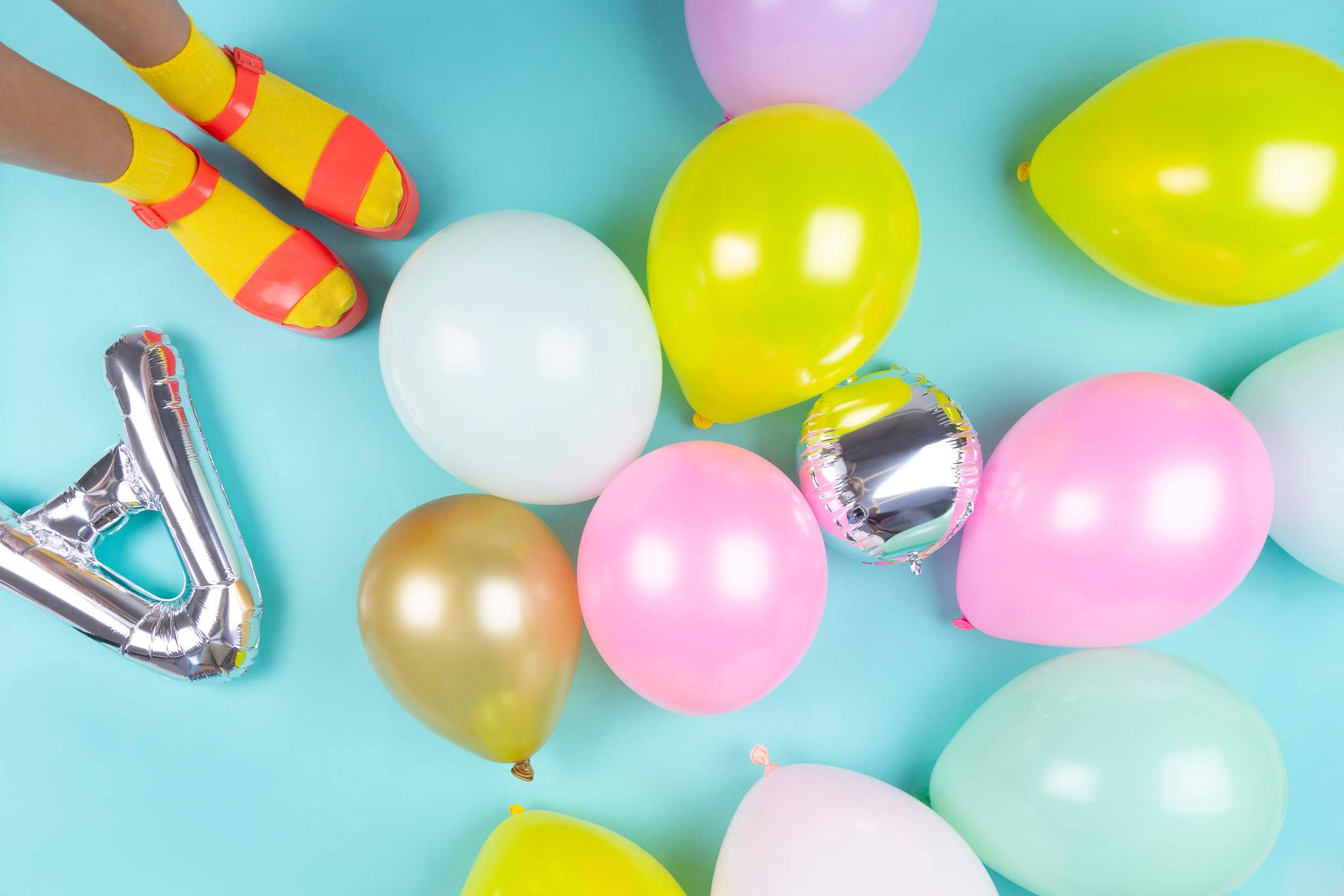 Colourful balloons and party decorations lie across a turquoise surface.