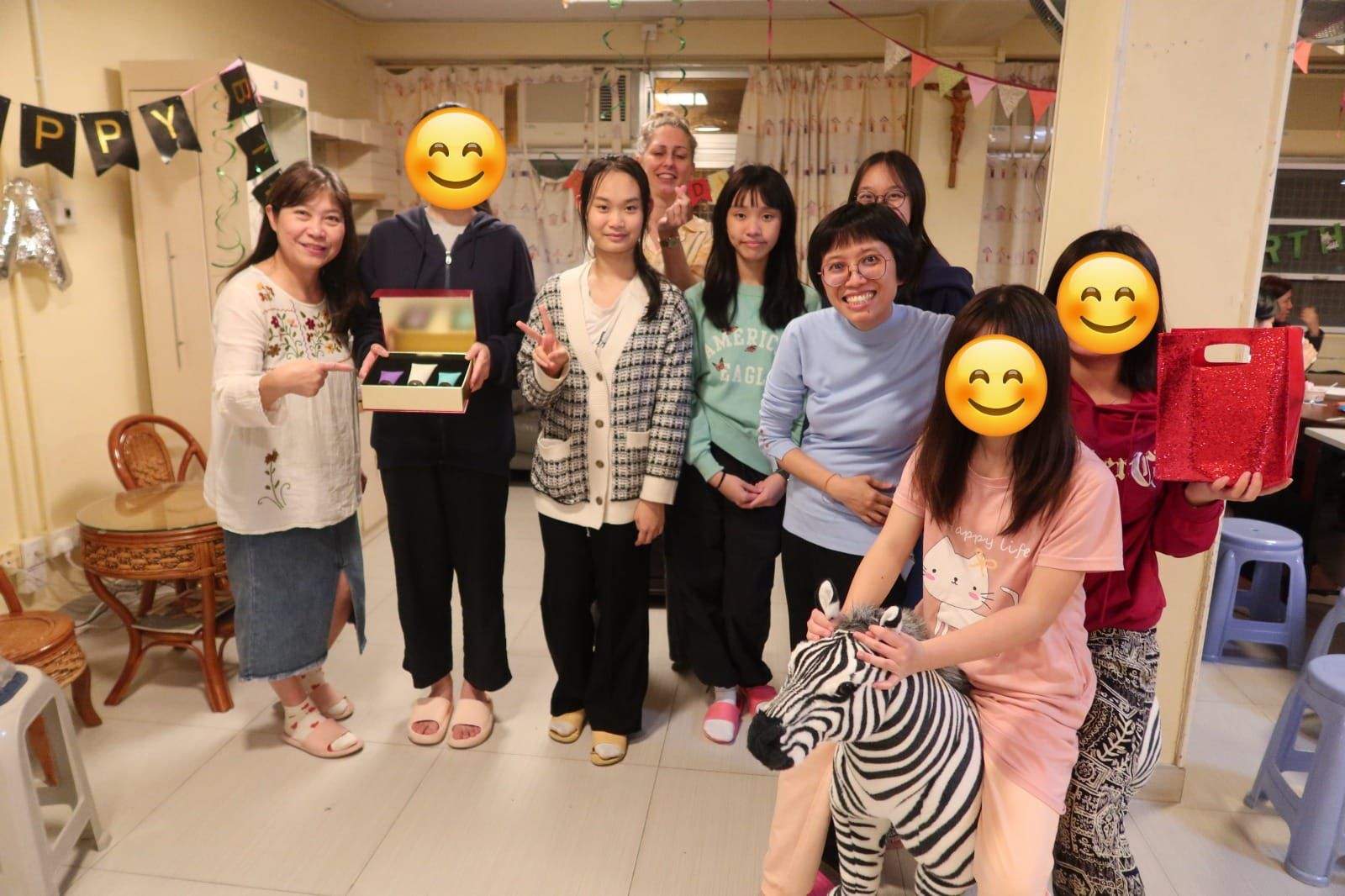 A group of adults and children poses with gifts and toys.