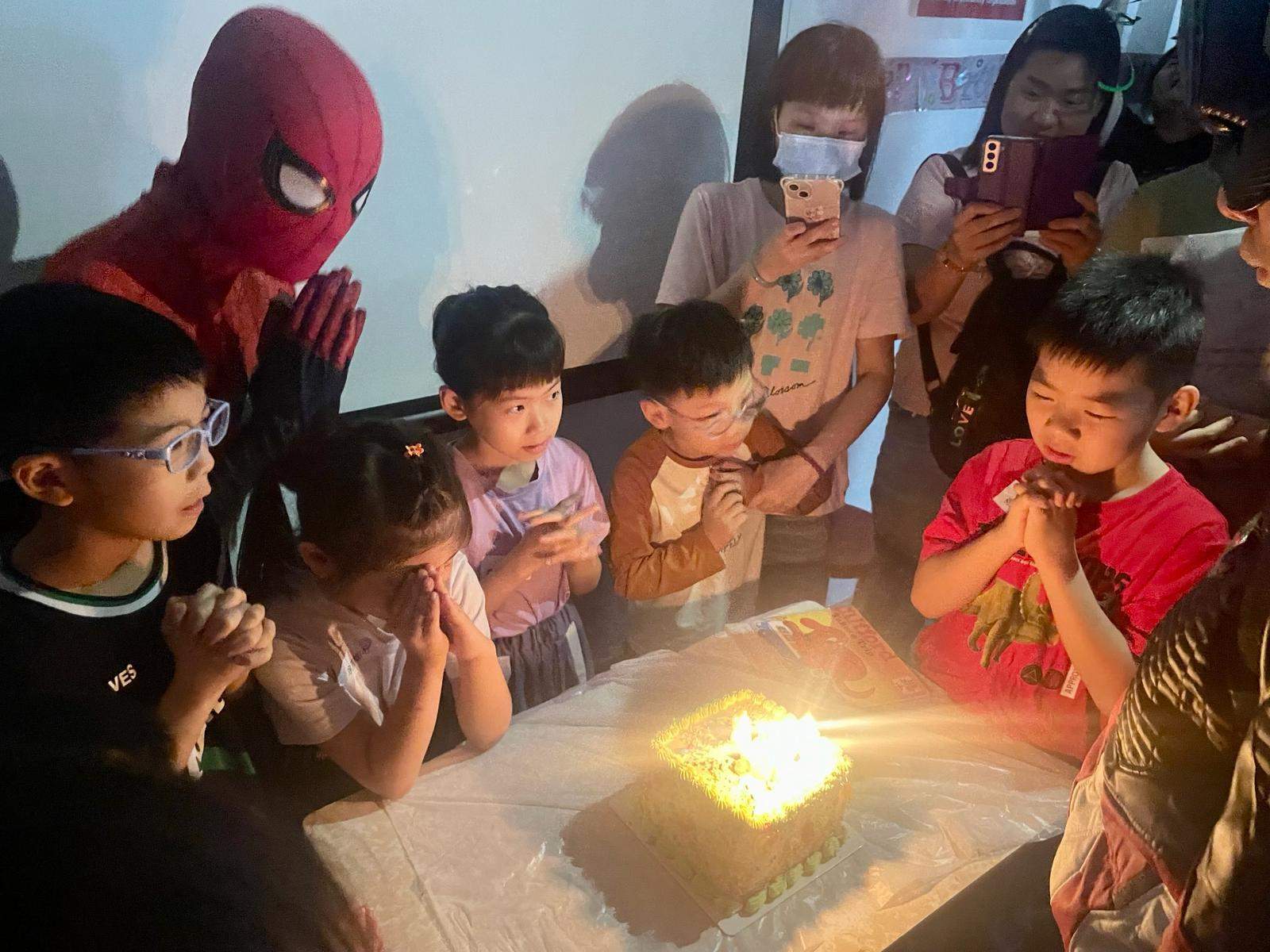 Children gather around a cake glowing with candles.
