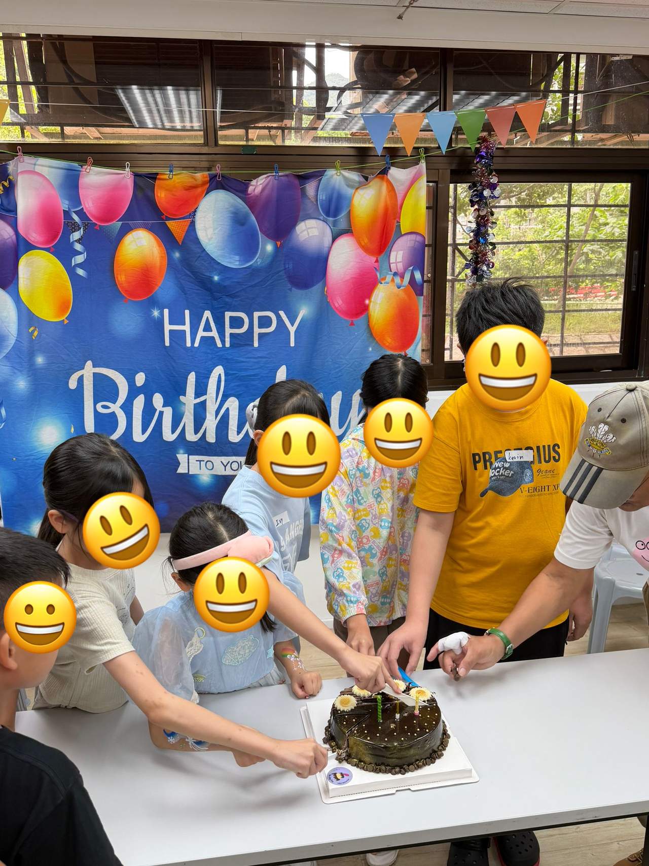 A group cuts a birthday cake beneath colourful decorations.