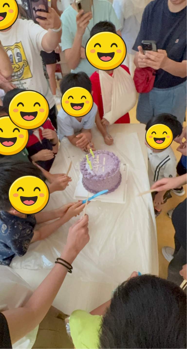 A group gathers around the cake during the cutting moment.