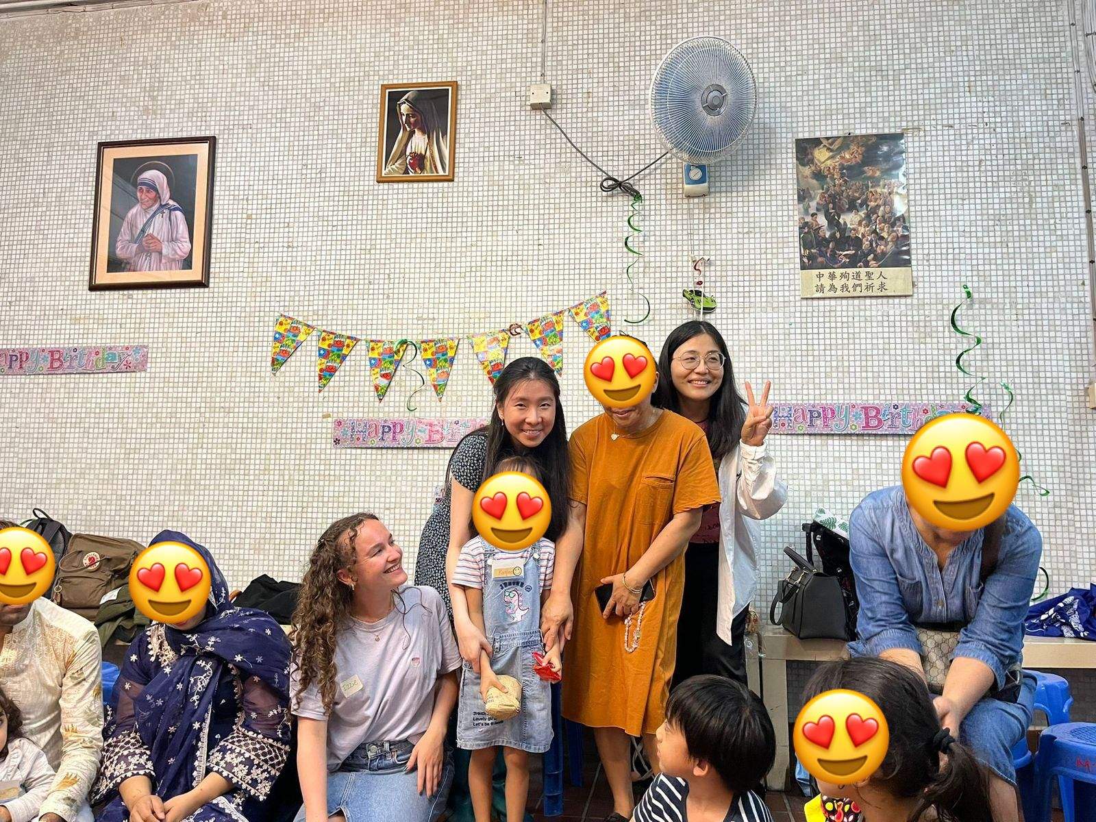 Adults and children pose together beneath birthday bunting.