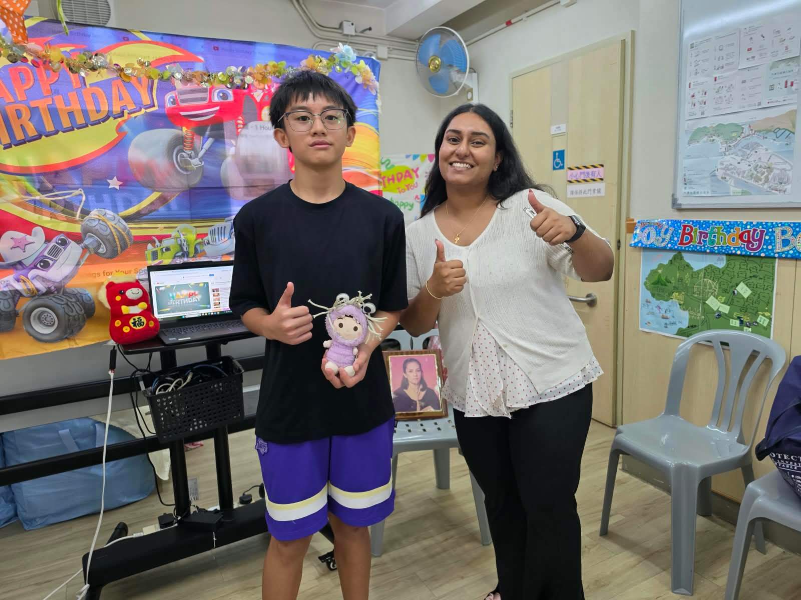 A volunteer poses with a child holding a handmade toy.