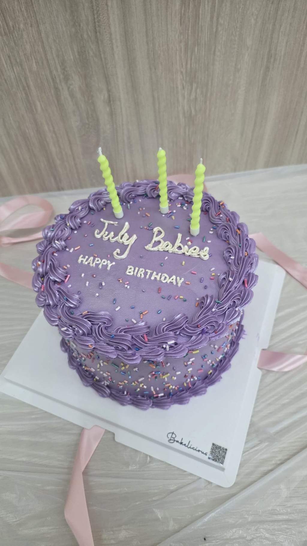 An uncut purple birthday cake is displayed with four candles.