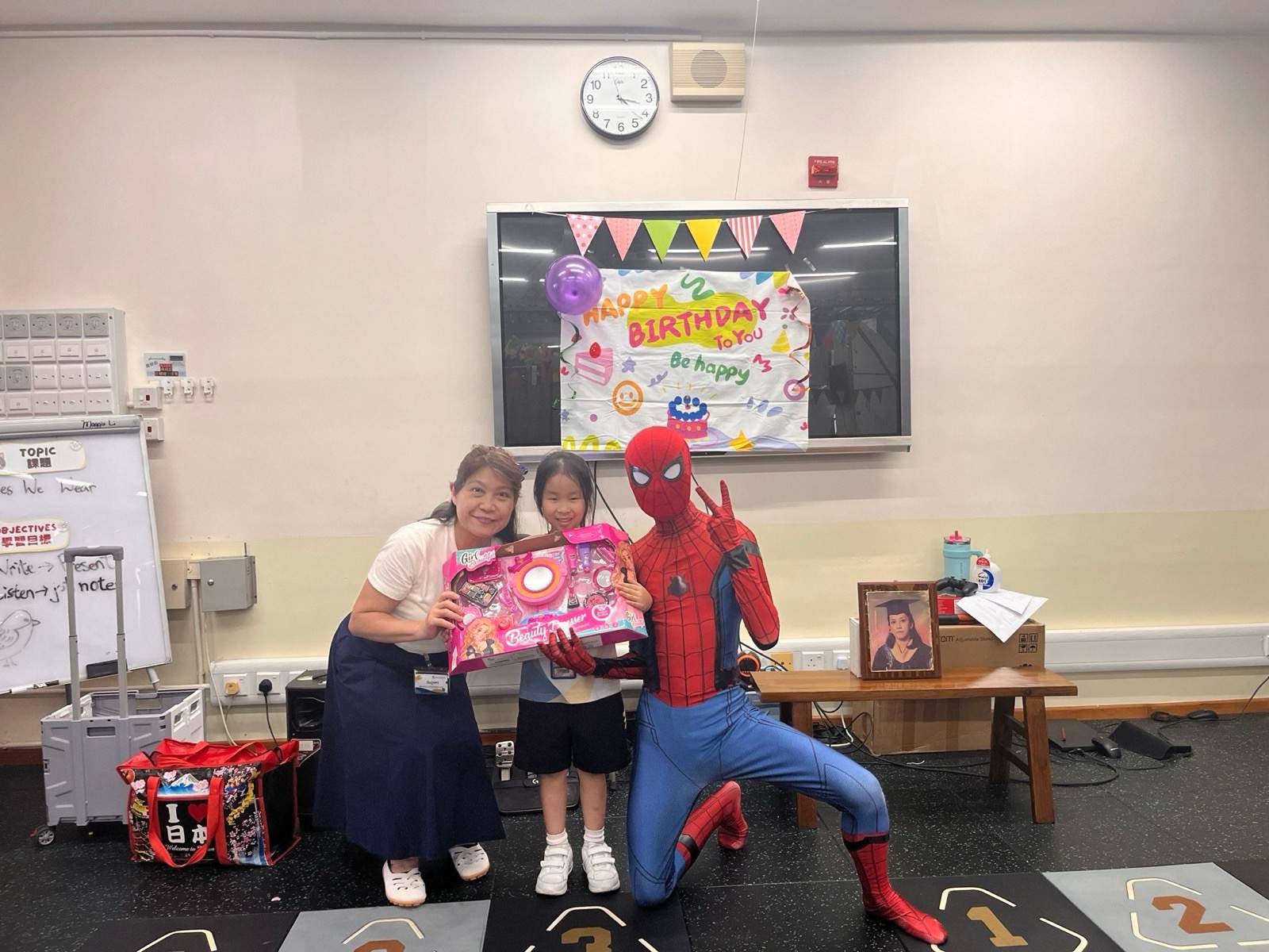 An adult and costumed performer pose with a child holding a gift.