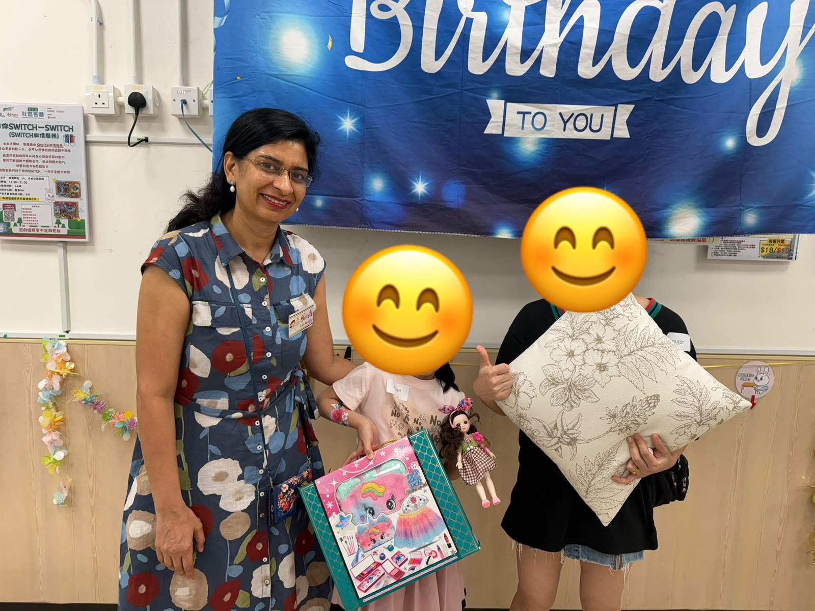 An adult stands beside two children displaying wrapped gifts.