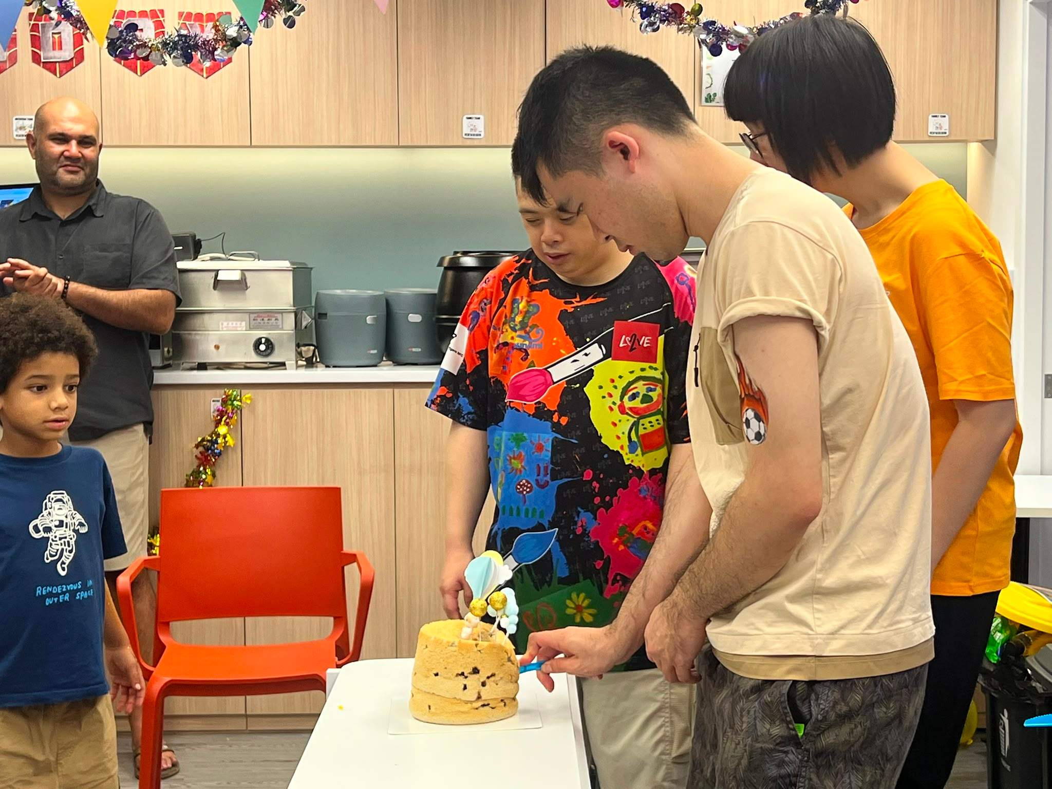 Three people stand together while cutting a decorated cake.