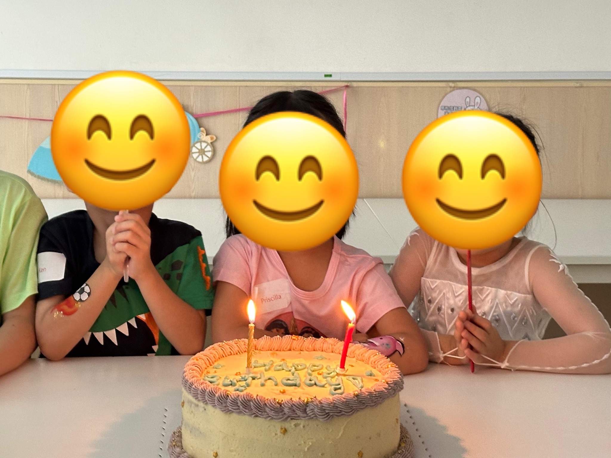 Three children sit behind a cake with lit candles.