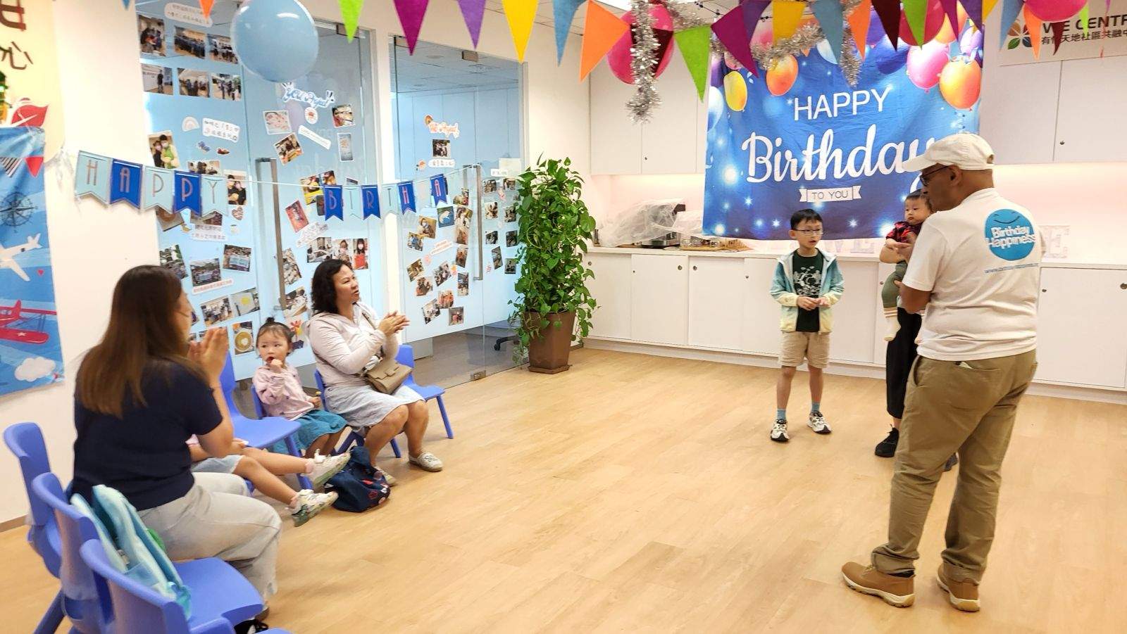 A seated group watches an adult lead an activity.