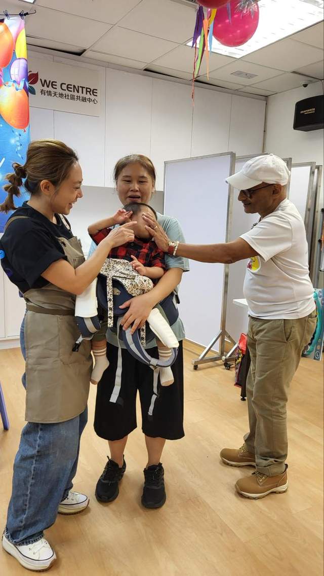 Three adults gather around a child holding a small cake.