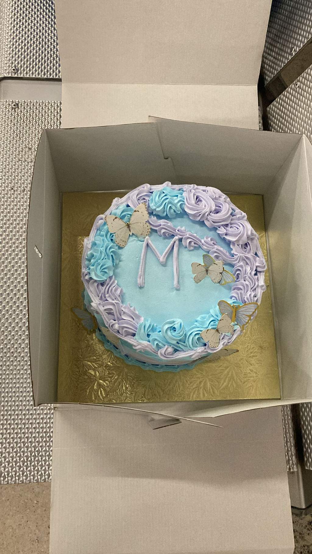 A decorated birthday cake rests inside an open cake box.