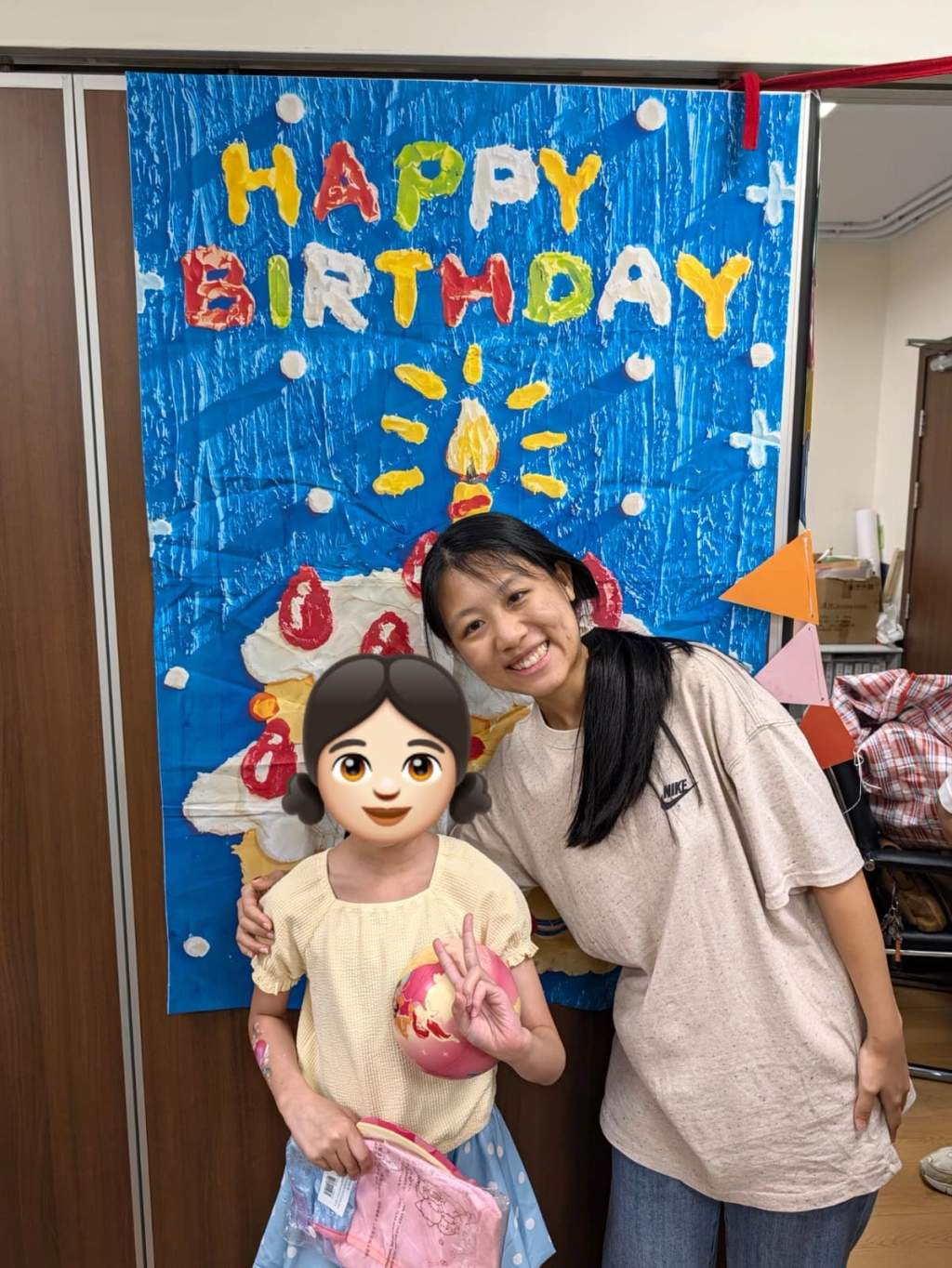 A child and volunteer pose together beside the birthday backdrop.