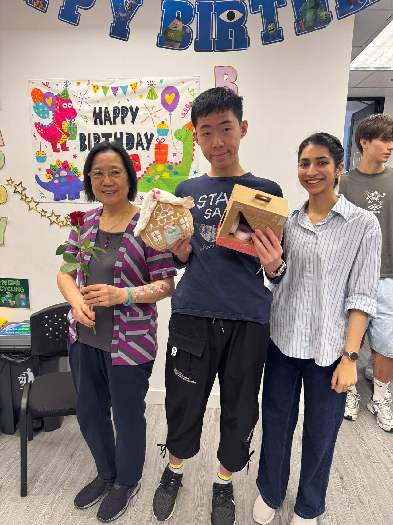 Two adults stand beside a person holding a gift box.