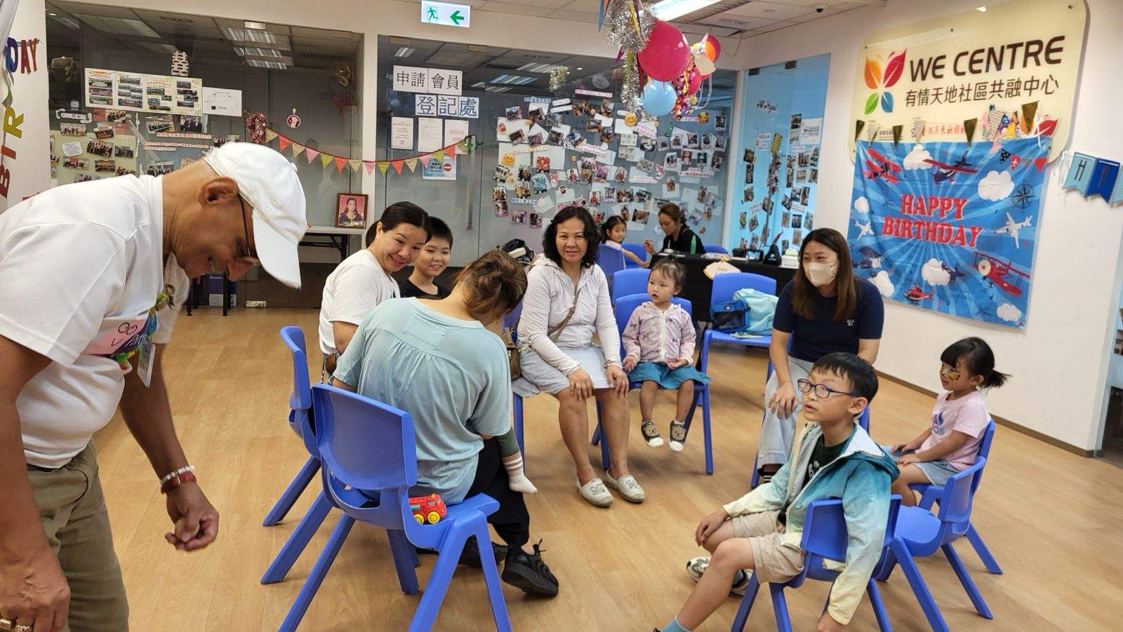 Adults and children sit in a circle during a group activity.
