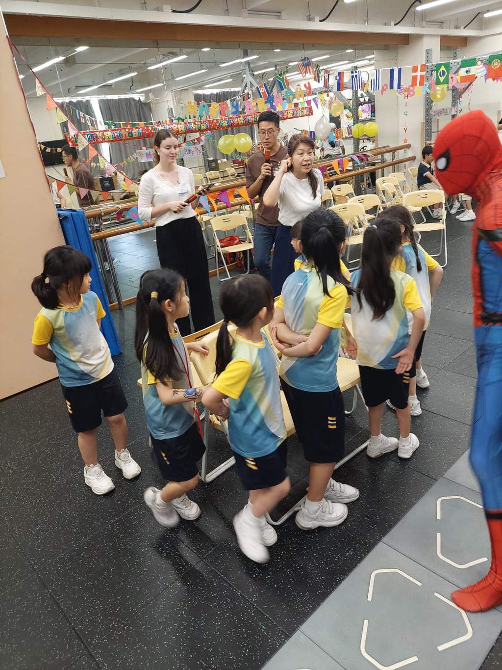 Children queue together while adults watch the activity.