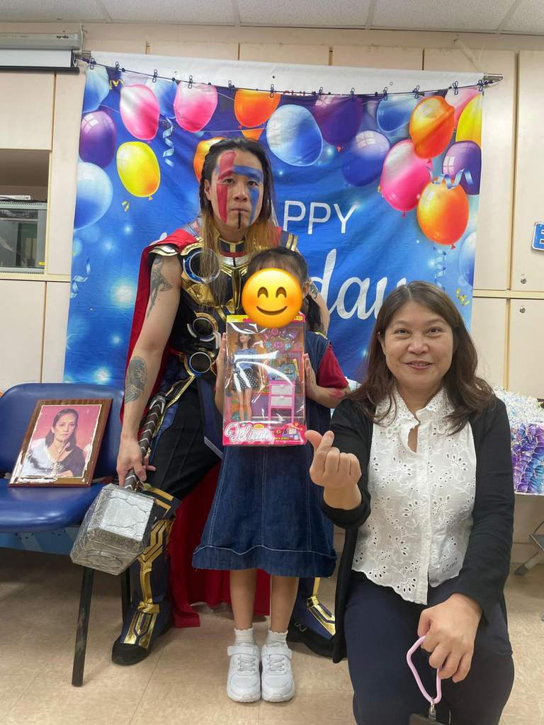A costumed performer and adult pose beside a child with gifts.