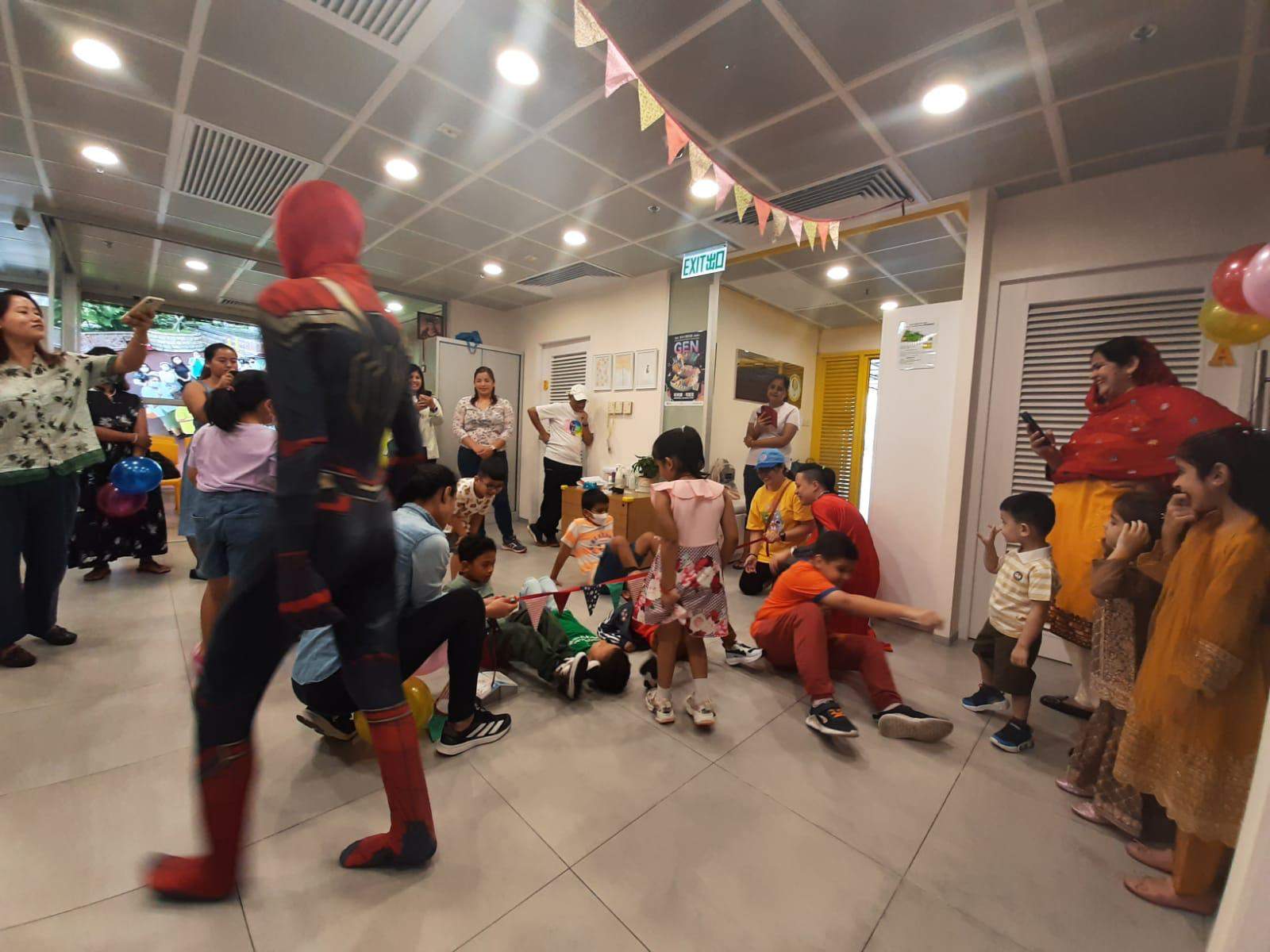 A costumed performer walks through a circle of seated children.