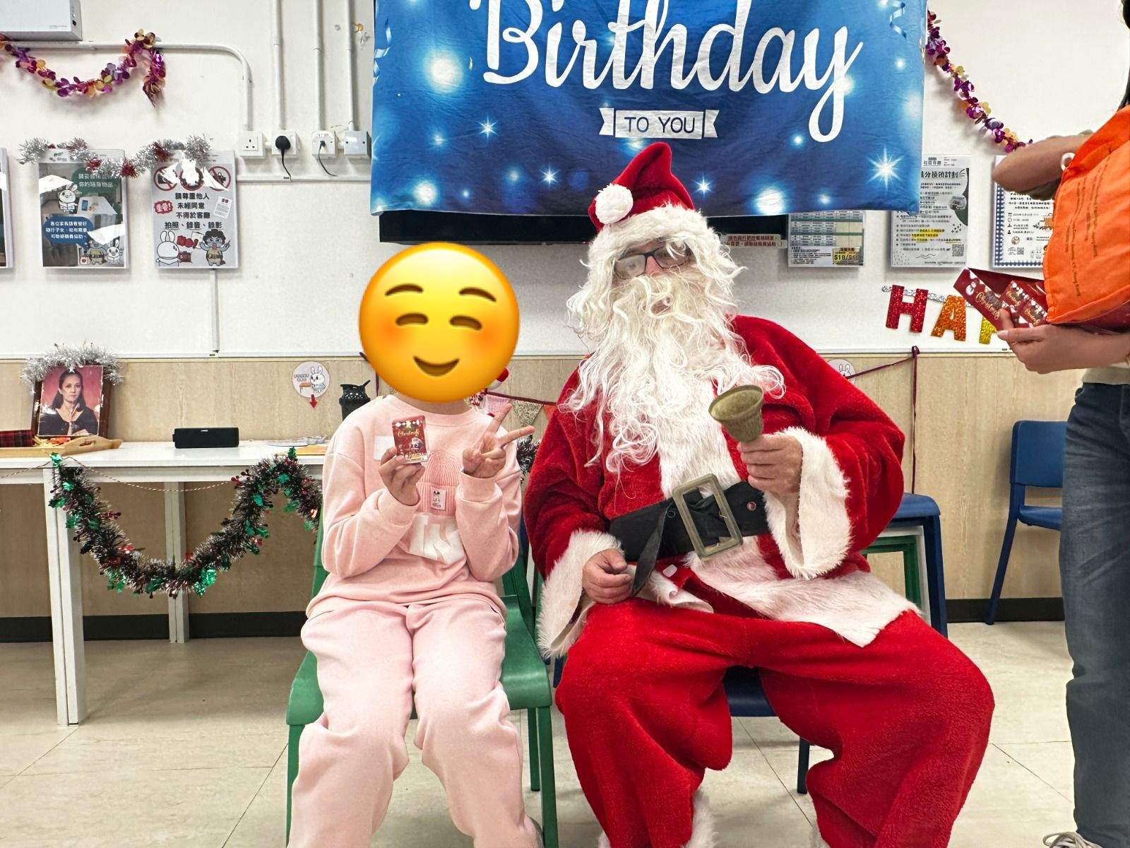 A child sits beside a costumed adult beneath birthday decorations.