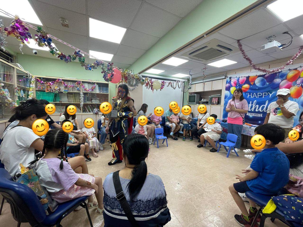 A costumed performer addresses adults and children seated in a circle.