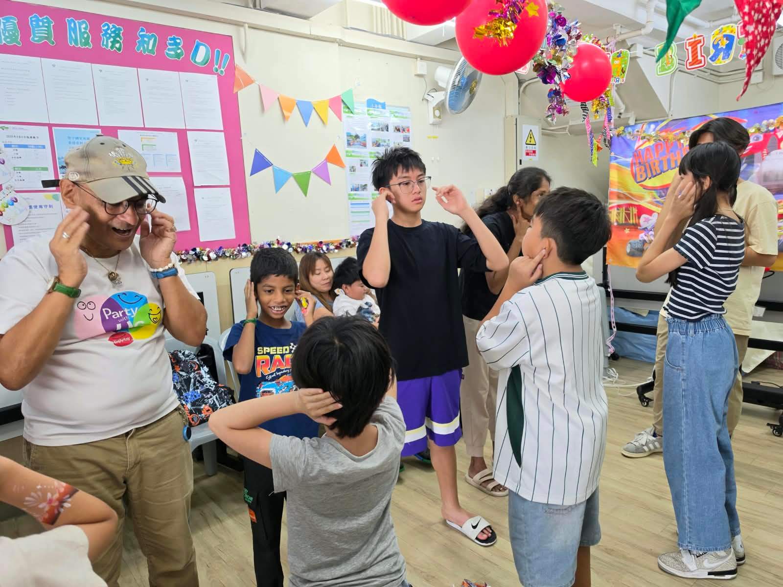 Children and volunteers follow gestures during a group game.