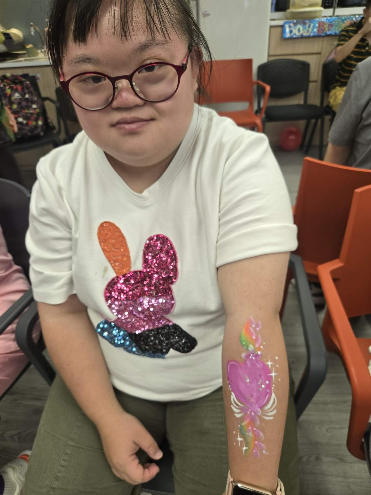 A participant shows colourful artwork painted along an arm.