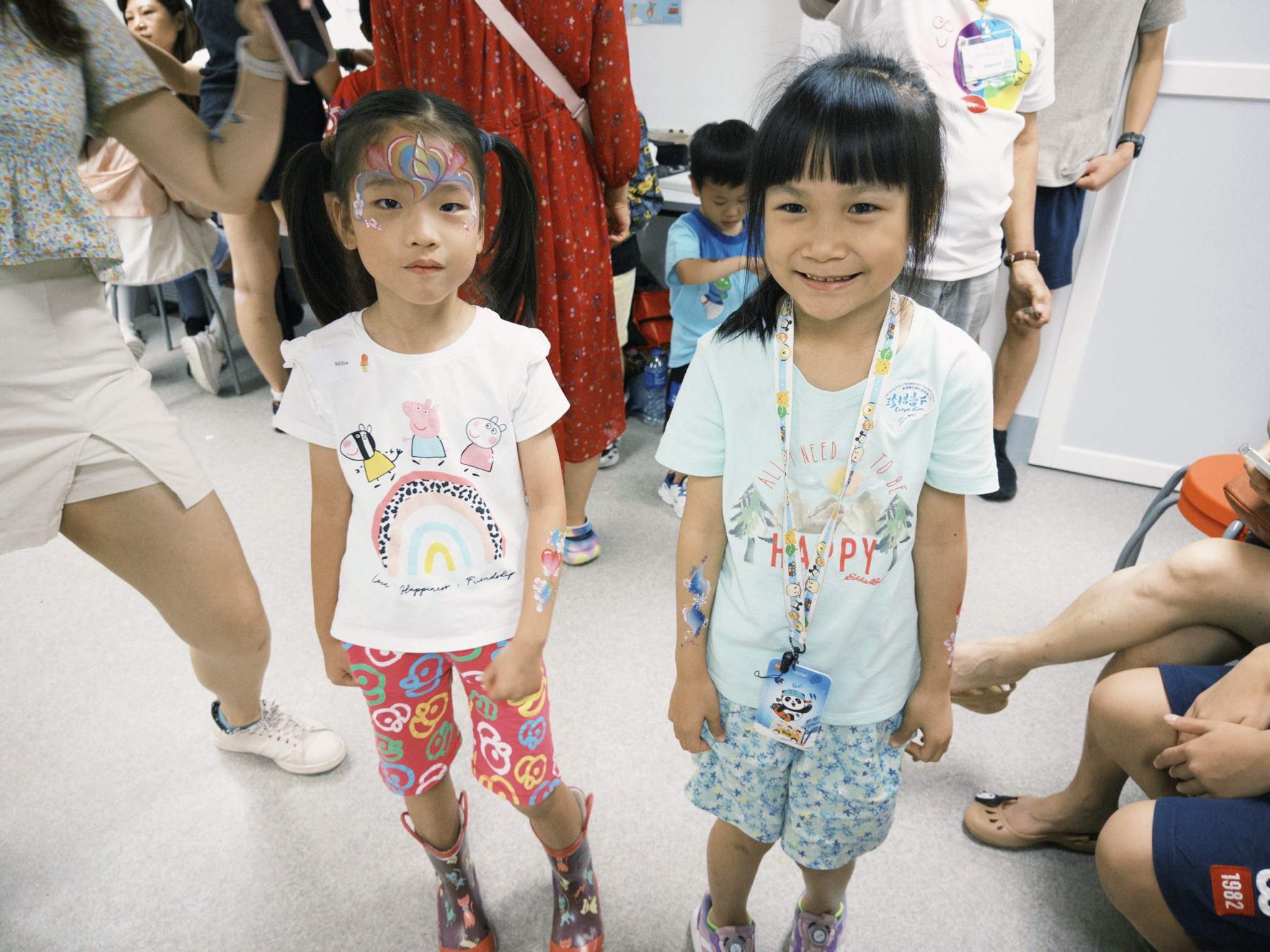 Two children stand together displaying painted face designs.