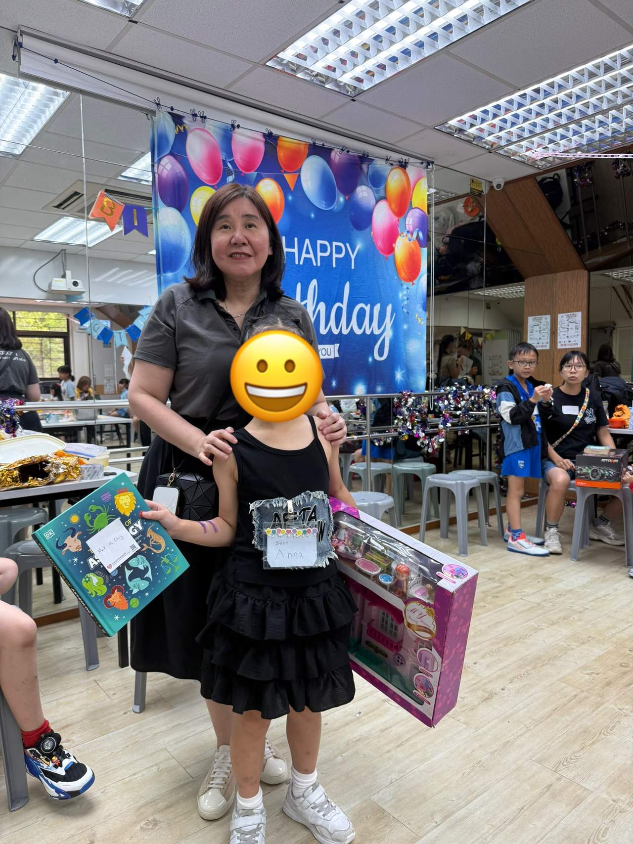 An adult and child pose with several boxed gifts.