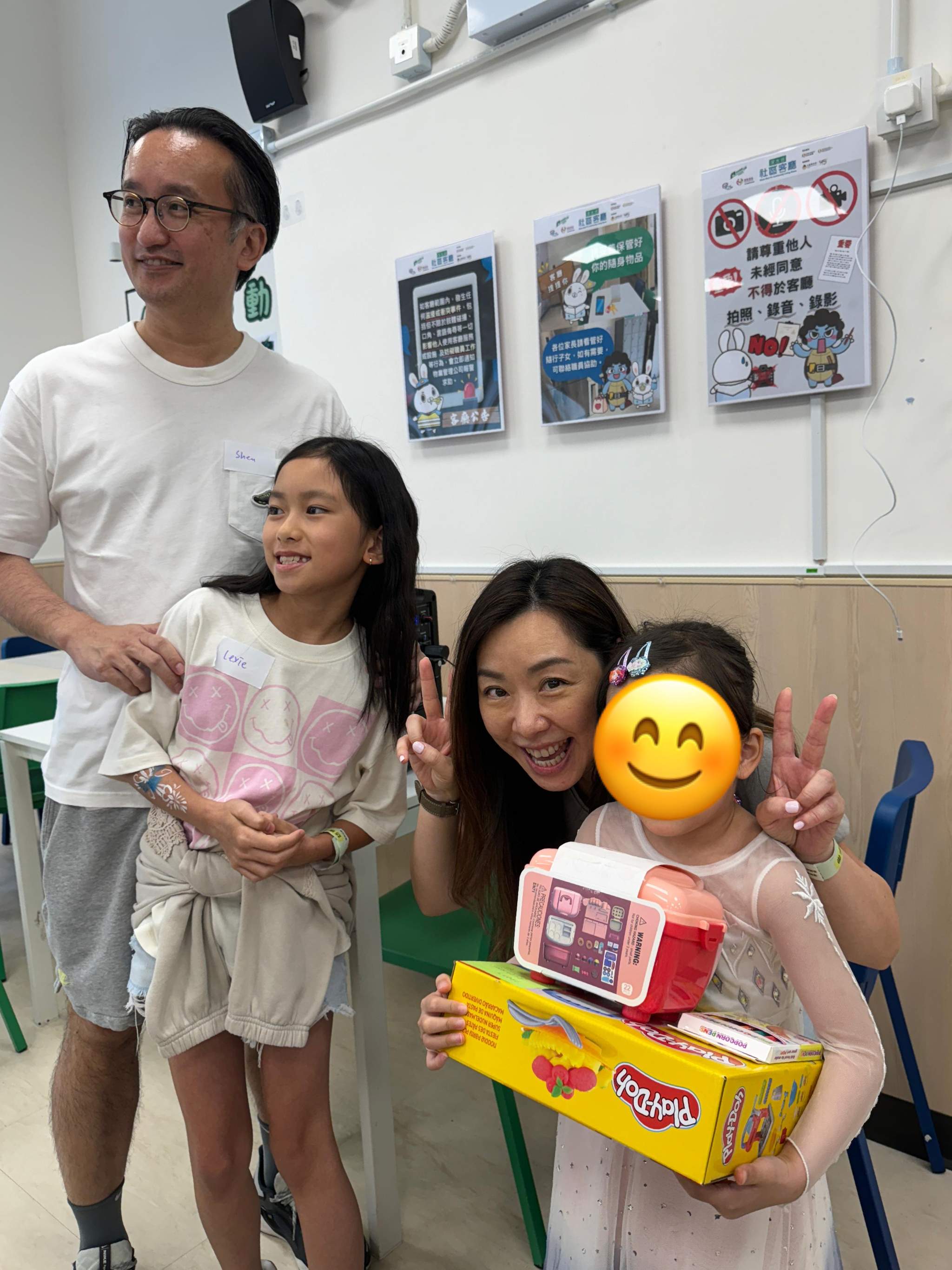 Adults and children pose together with a boxed gift.