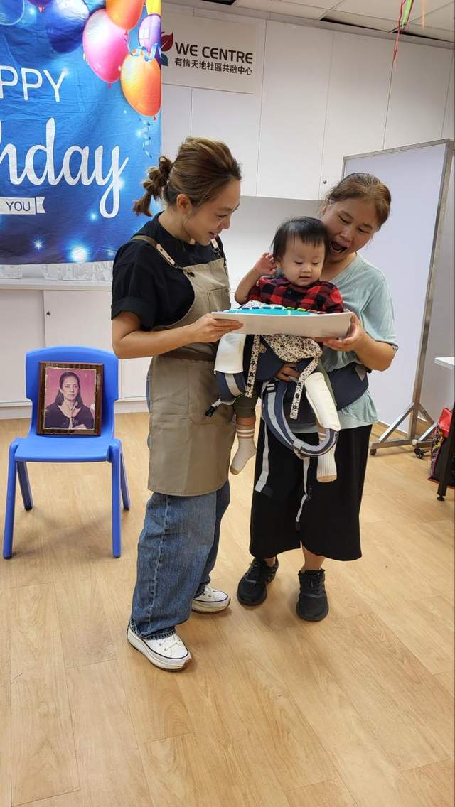 Two adults stand with a child holding a decorated cake.