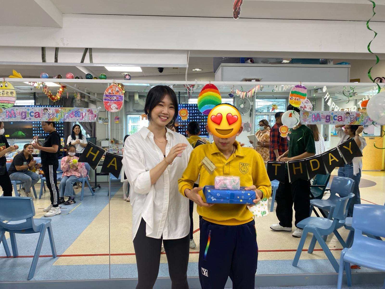 An adult poses beside a participant holding a boxed gift.