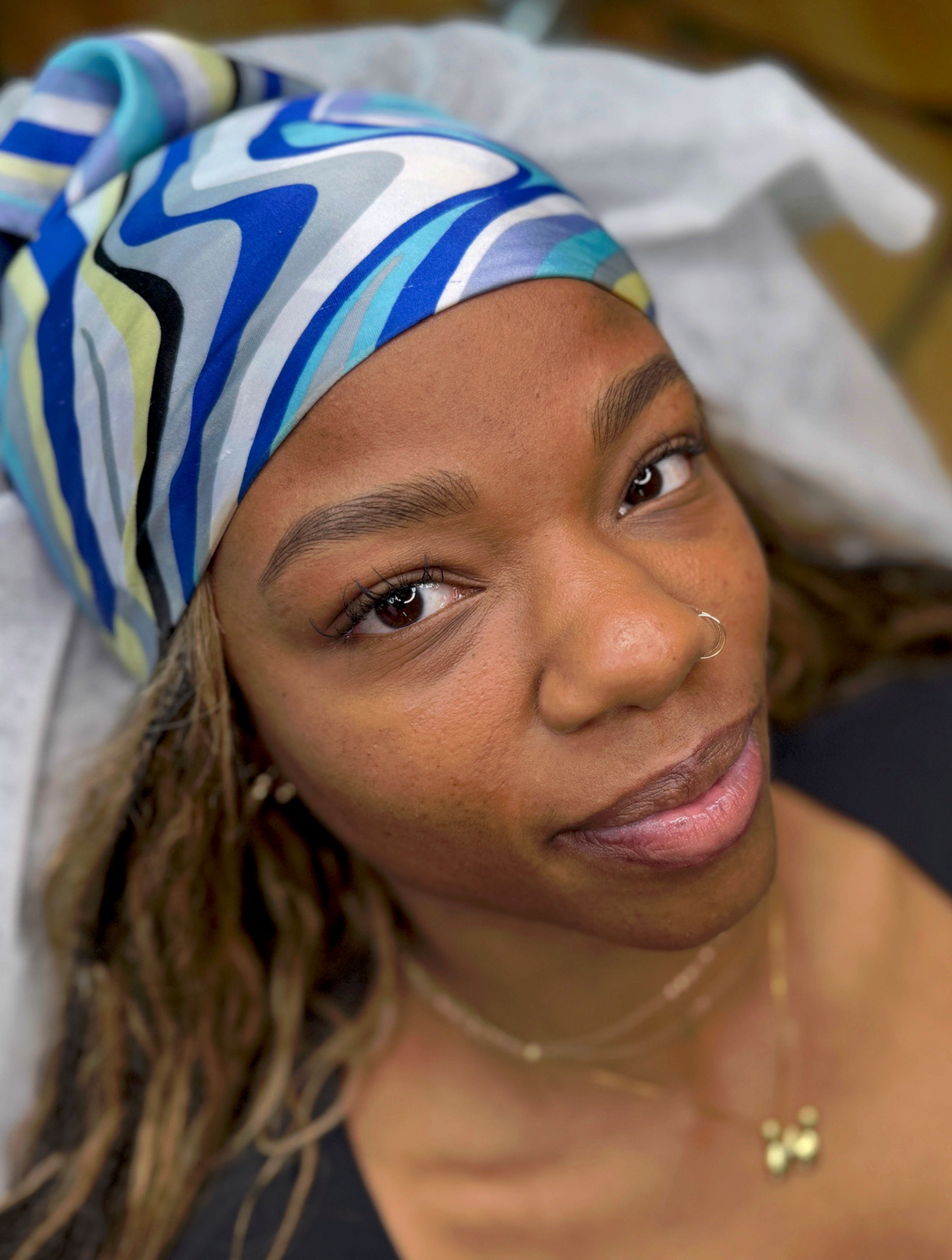 Close-up of a nano brow with ultra-fine, hair-like strokes creating a natural, full eyebrow next to a brown eye with long lashes.